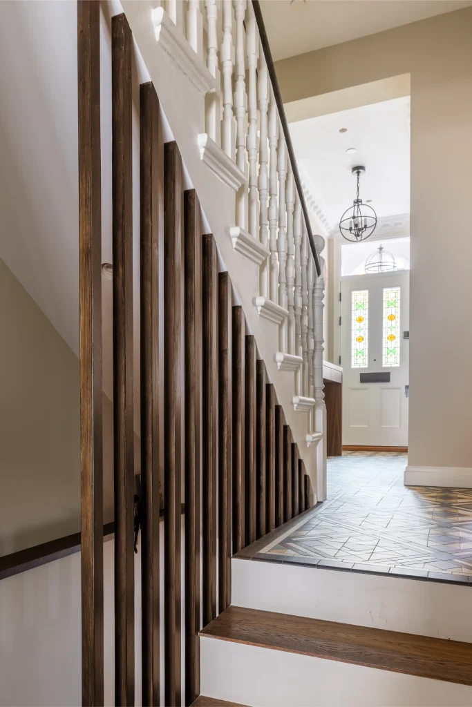 Modern London hallway with staircase, wooden railings and patterned floor tiles