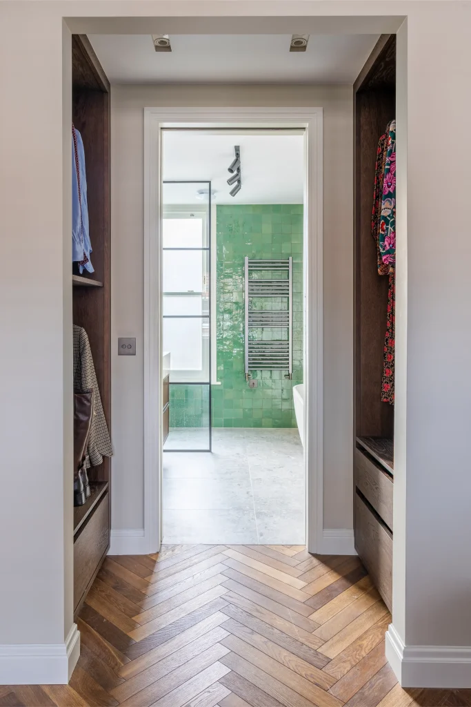 Project London interior with walk-in wardrobe, herringbone floor and green bathroom beyond in Hurlingham Park
