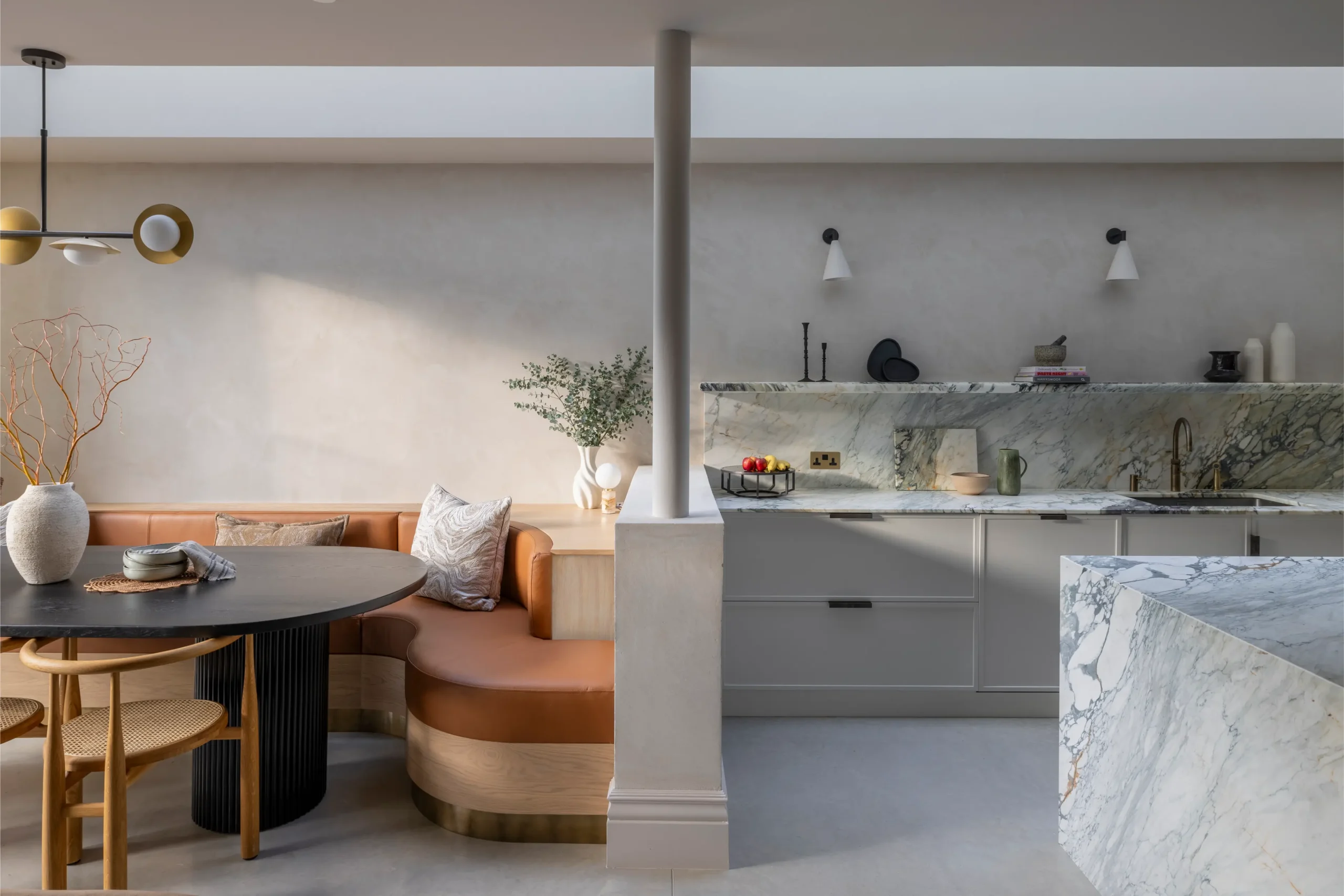 Open-plan kitchen in Mallorcan-inspired London home featuring marble worktops, soft plaster finishes and custom seating