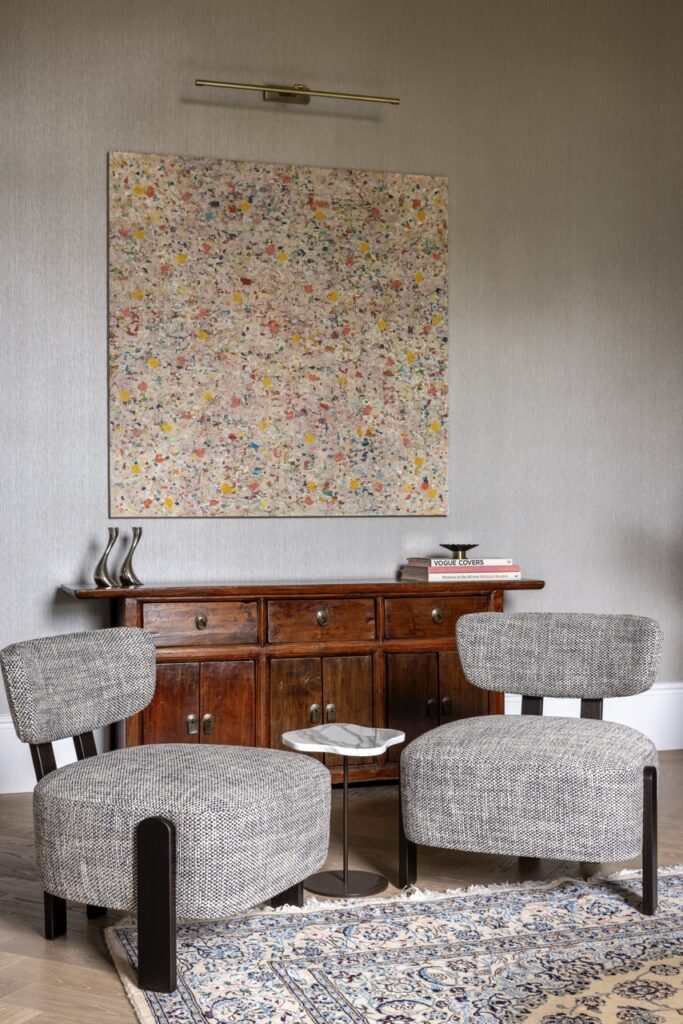 Luxury London home seating area with bouclé chairs, antique sideboard, and large canvas artwork