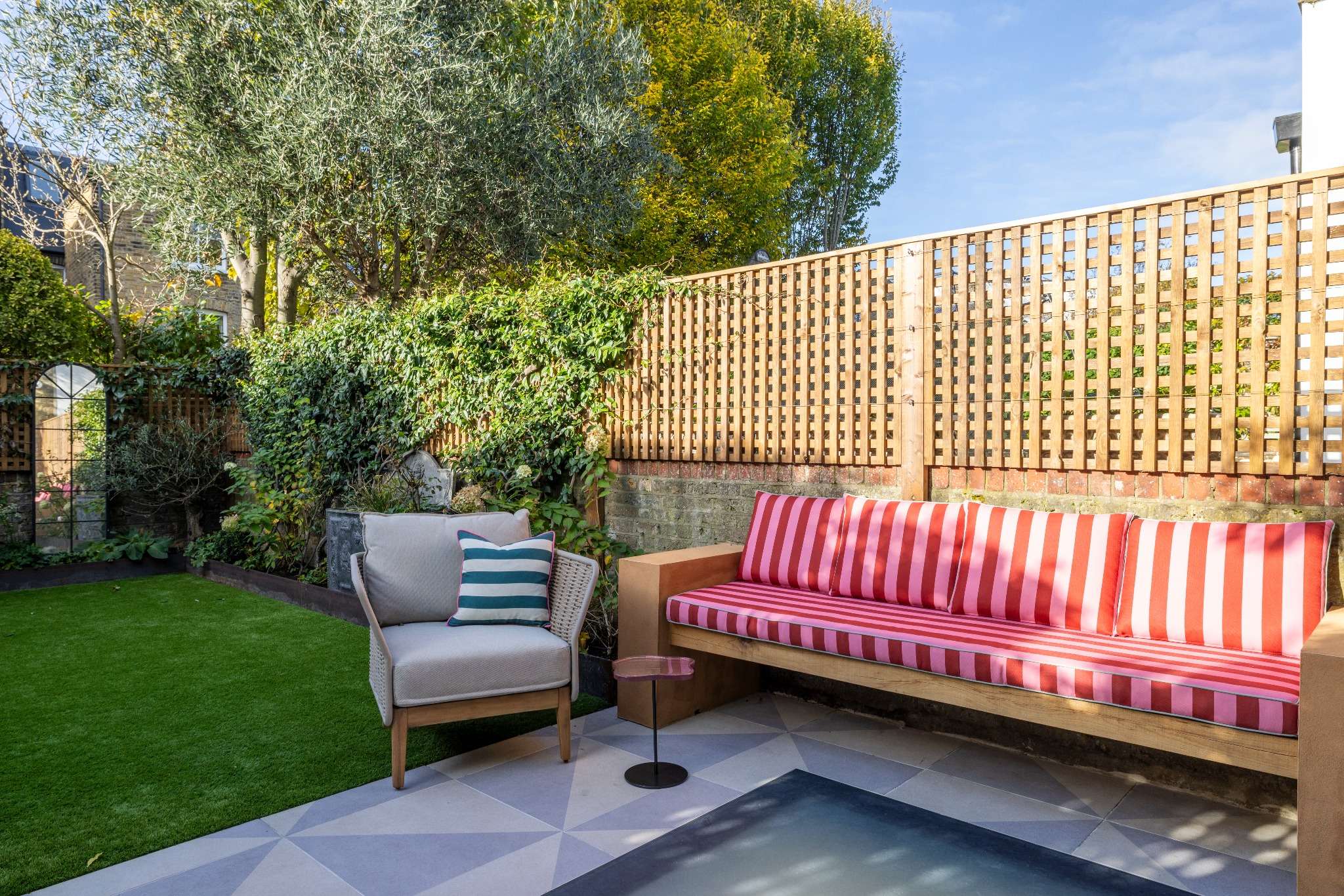 Modern Bradbourne courtyard: custom garden seating, outdoor armchair, lawn, and architectural roof light